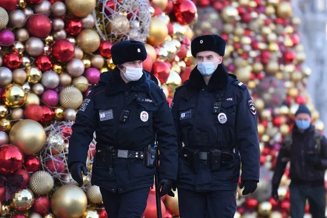 Russian police officers wearing face masks patrol past festive decorations for the upcoming New Year and Christmas holidays in Moscow on December 9, 2020, amid the ongoing coronavirus disease pandemic. (Photo by Natalia Kolesnikova/AFP Photo)
