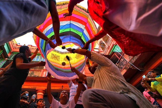 A group of people seen holding a paper lantern during the celebration of the Diwali festival on October 20, 2025. The Fanush, a paper-made hot air balloon, is an integral part of North Calcutta Heritage Culture, and it is an old tradition to fly Fanuash on the day of Kalipujo before Diwali in Kolkata. (Photo by Avishek Das/SOPA Images/Rex Features/Shutterstock)