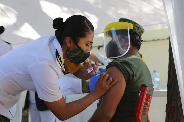 Nurse Mercedes Jose applies the COVID-19 vaccine to a soldier at The Heroic Military College in Mexico City, Sunday, December 27, 2020. The second batch of vaccines produced by Pfizer and its German partner, BioNTech, arrived to Mexico on Saturday. (Photo by Ginnette Riquelme/AP Photo)