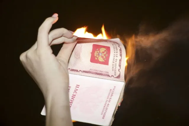A demonstrator burns her Russian passport during a pro-Ukraine protest outside the Russian Embassy in Tel Aviv, Israel, Thursday, February 24, 2022, after Russia launched an invasion of Ukraine. (Photo by Gideon Markowicz/AP Photo)