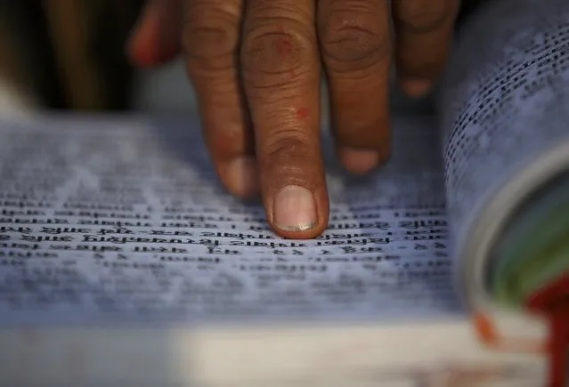 A Hindu holy man holds the holy Swasthani Brata Katha as he recites verses from the book at the bank of River Saali in Sankhu on the first day of Swasthani Brata Katha festival in Kathmandu January 5, 2015. (Photo by Navesh Chitrakar/Reuters)