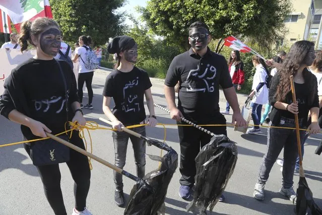 Protesters with their faces blackened, walk carrying broomsticks covered in garbage bags during a demonstration against what they said was political corruption and the government's failure to resolve a waste disposal crisis, on Lebanon's Independence Day in Beirut, Lebanon November 22, 2015. The Arabic words on the T-shirts read, (R-L), "Corrupt minister, leader from 60 years, bribe". (Photo by Aziz Taher/Reuters)