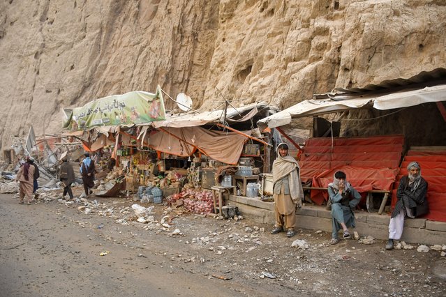 Shopkeepers sit in front of their damaged shops along a highway, following an earthquake at the Tang-e Tashkurgan in the Khulm district of Samangan province on November 3, 2025. A strong earthquake killed at least 20 people in northern Afghanistan, authorities said on November 3, just months after another deadly tremor that left the country reeling. (Photo by Atif Aryan/AFP Photo)