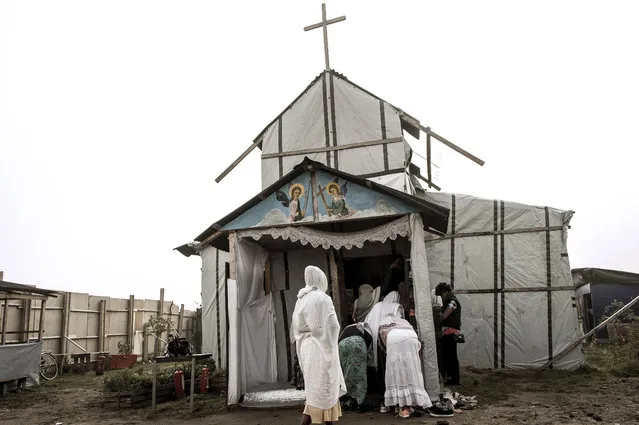 Ethiopian Coptic migrants arrive for a mass at the makeshift Orthodox church in the “Jungle” migrant camp, on October 30, 2016 in Calais, northern France. French President Francois Hollande on October 29, 2016 urged Britain to take in 1,500 unaccompanied minors from the “Jungle” as officials stepped up efforts to finish demolishing the almost-deserted Calais migrant camp. Hailing the evacuation of the sprawling encampment, Hollande vowed that France would not accept the emergence of any more makeshift camps, which have become a glaring symbol of Europe's worst migration crisis since World War II. (Photo by Philippe Huguen/AFP Photo)