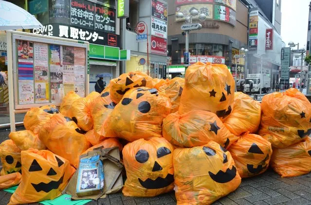 Jack-o'-lantern plastic bags filled with trash left by costumed partygoers are piled up on a sidewalk in Shibuya Ward, Tokyo, Japan early Tuesday, November 1, 2016. (Photo by Kyodo News)
