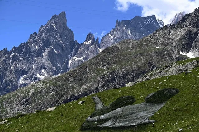 French Land artist Guillaume Legros aka “Saype” works on his new giant land art fresco entitled: “La Grande Dame” (The Great Lady) in Courmayeur, next to the Mont Blanc, on July 3, 2023. The artwork is created with biodegradable paint made from chalk charcoal, water and milk protein. (Photo by Gabriel Bouys/AFP Photo)