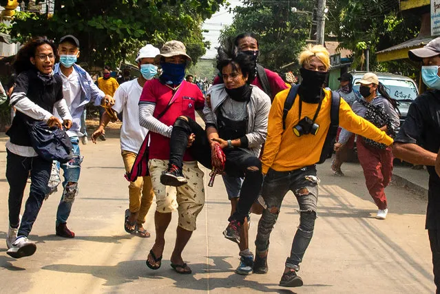 Protesters carry an injured comrade during a demonstration against the military coup in Yangon's Thaketa township on March 29, 2021. (Photo by AFP Photo/Stringer)