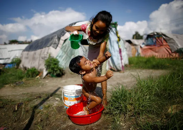 A girl showers her sister at the displacement camp for earthquake victims at Chuchepati in Kathmandu, Nepal, September 19, 2016. Picture taken September 19, 2016. (Photo by Navesh Chitrakar/Thomson Reuters Foundation)