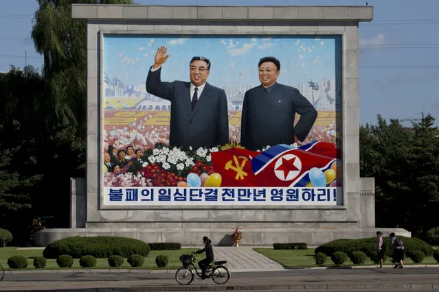 A woman cycles past a mural showing late North Korean leaders Kim Il Sung and Kim Jong Il as the capital prepares for the 70th anniversary of North Korea's founding day in Pyongyang, North Korea, Friday, September 7, 2018. (Photo by Ng Han Guan/AP Photo)
