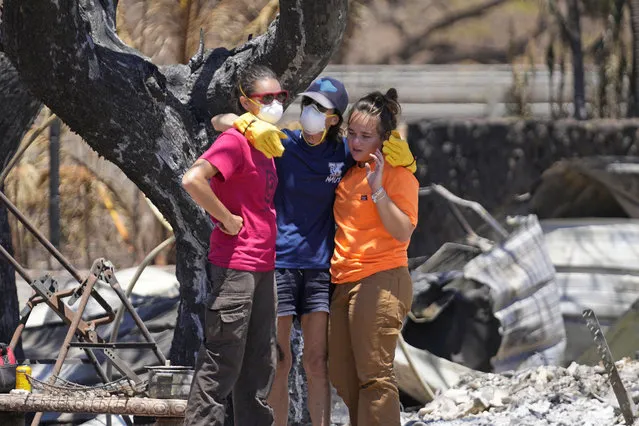 Women hug after digging through rubble of a home destroyed by a wildfire on Friday, August 11, 2023, in Lahaina, Hawaii. (Photo by Rick Bowmer/AP Photo)