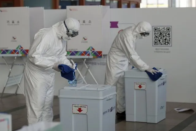 Workers wearing protective gears disinfect as a precaution against the coronavirus ahead of the early voting for the upcoming Seoul mayoral by-election at a local polling station in Seoul, South Korea, Thursday, April 1, 2021. The early voting for the April 7 Seoul and Busan mayoral by-election will be held for two-days on April 2-3. (Photo by Lee Jin-man/AP Photo)