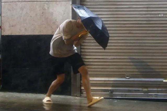 A man with an umbrella struggles against strong wind and rain brought by super typhoon Saola in Hong Kong, on Friday, September 1, 2023. (Phoot by Daniel Ceng/AP Photo)
