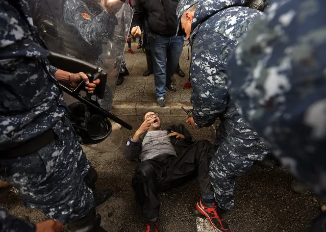 Lebanese policemen hit an anti-government protester outside the Environment Ministry during a demonstration in support of activists who were detained after staging a sit-in inside, in downtown Beirut, Lebanon, Thursday, January 14, 2016. Lebanon's trash collection crisis which set off huge protests in the summer is still festering, with no immediate solution on the horizon. (Photo by Bilal Hussein/AP Photo)