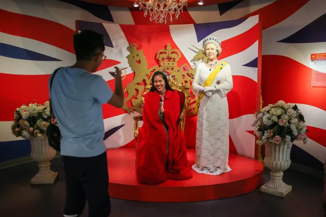 A picture made available on 09 December 2016 shows a woman posing with a wax figure of Britain's Queen Elizabeth II at the Madame Tussauds wax museum in Bangkok, Thailand, 26 November 2016. (Photo by Diego Azubel/EPA)