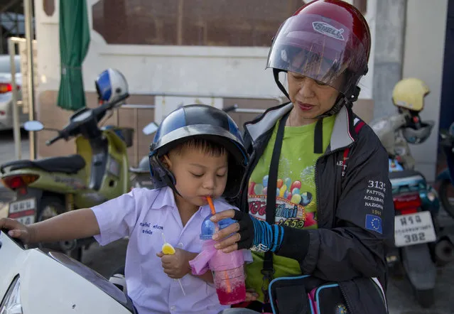 In this Thursday, November 1, 2018, photo, a woman feeds a child with a sweeten fuzzy drink and a candy as she picks him up after school in Bangkok, Thailand. A report by the United Nations Food and Agricultural Organization released Friday says some 486 million people are malnourished in Asia and the Pacific, and progress in alleviating hunger has stalled. More than half of all children who are malnourished live in the region, with stunting that causes long-term damage worsened by food insecurity and inadequate sanitation, even in Bangkok, more than a third of children were not receiving an adequate diet as of 2017, the report said.(Photo by Gemunu Amarasinghe/AP Photo)