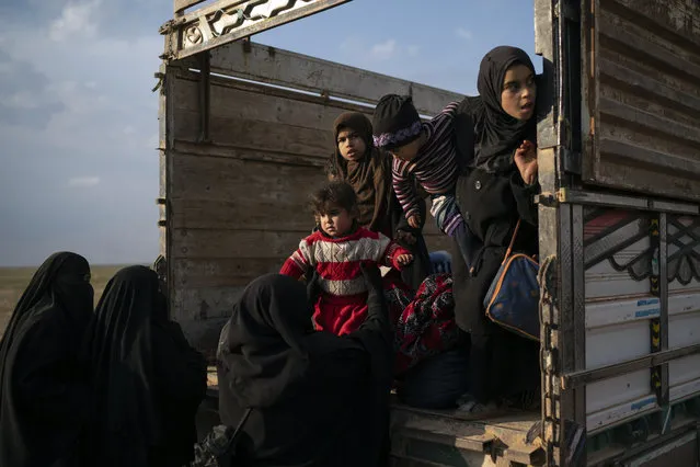 Women and children exit the back of a truck, part of a convoy evacuating hundreds out of the last territory held by Islamic State militants in Baghouz, eastern Syria, Friday, February 22, 2019. (Photo by Felipe Dana/AP Photo)
