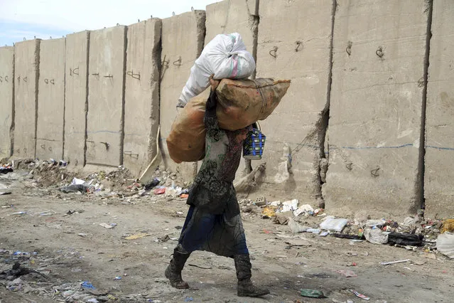 Zahra Hamid, 15, carries recyclable items at a garbage dump in Baghdad, Iraq, Thursday, March 3, 2016. Most workers in the garbage dump are widows and orphans who live below the poverty line. Zahra Hamid, who lost her father in a car bomb explosion left her school to support her family. (Photo by Karim Kadim/AP Photo)