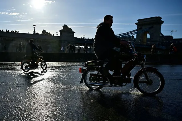 People ride their motorbikes on a quay flooded by the Danube River in Budapest, Hungary on December 27, 2023. (Photo by Marton Monus/Reuters)