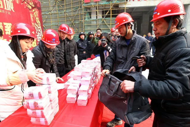 Migrant workers collect their salary and bonus ahead of the Spring Festival at a construction site in Xi'an, Shaanxi province, China, Janauary 18, 2017. (Photo by Reuters/Stringer)