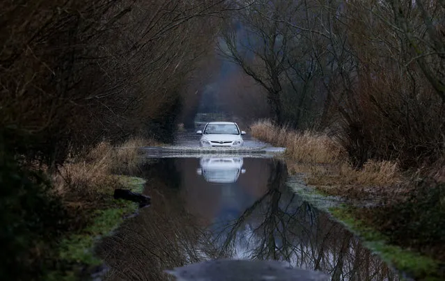 A car drives through flood water on the Somerset Levels on January 29, 2014 near Langport in Somerset, England. As weather forecasters predict more stormy weather, many villages on the Somerset Levels have faced weeks of flooding with the village Muchelney cut off because of flooded roads for almost a month. (Photo by Matt Cardy/Getty Images)