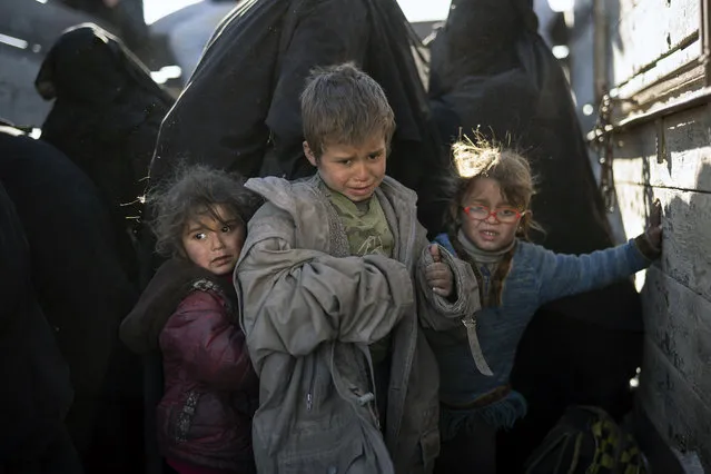 Women and children exit the back of a truck as they arrive to a U.S.-backed Syrian Democratic Forces (SDF) screening area after being evacuated out of the last territory held by Islamic State militants, in the desert outside Baghouz, Syria, Friday, March 1, 2019. (Photo by Felipe Dana/AP Photo)