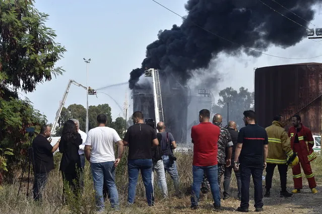 People watch firefighters extinguish a fire in one of the fuel tanks at the Zahrani facilities containing petrol in Zahrani, Lebanon, 11 October 2021. The cause of the fire is still yet to be known. (Photo by Wael Hamzeh/EPA/EFE)