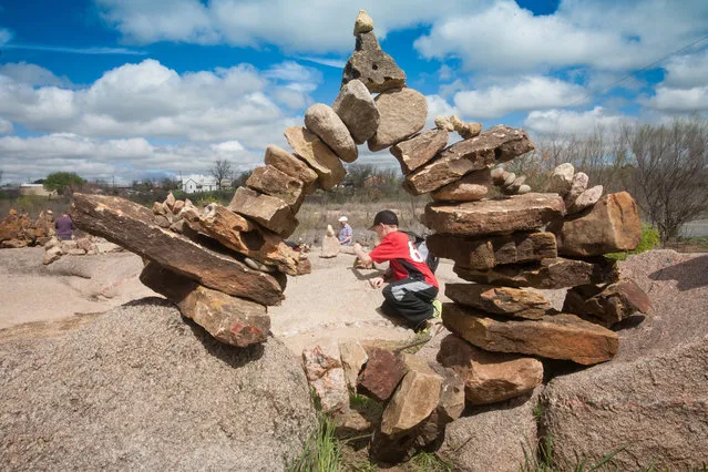 Shawn Fullerton, of Leander, seen through an arch of balanced rocks, works on his own small stack March 12, 2016 at the Llano Earth Art Fest. He and his brother Paul enjoyed stacking rocks on a open space near the arch. (Photo by Nell Carroll/American-Statesman)