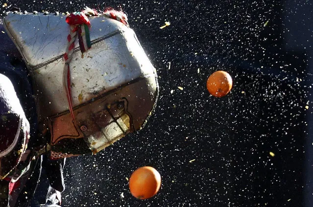A reveller takes part in a fight with oranges during an annual carnival battle in Ivrea, Italy, on February 11, 2024. (Photo by Guglielmo Mangiapane/Reuters)