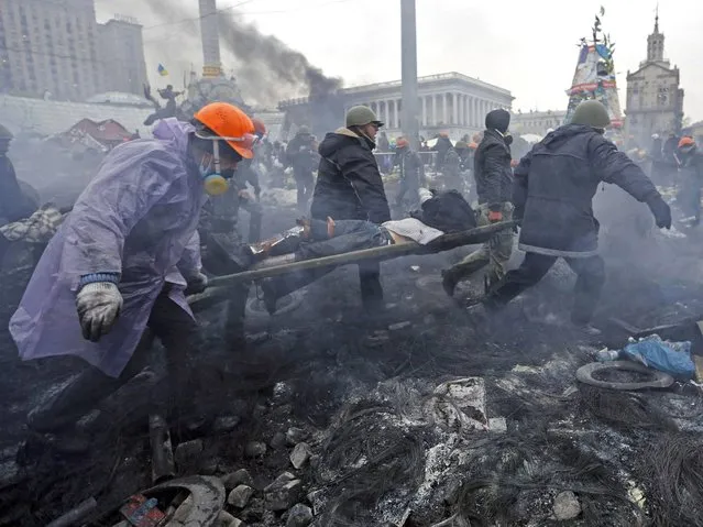 Anti-government protesters carry an injured man on a stretcher after clashes with riot police in the Independence Square in Kiev, on February 20, 2014. (Photo by Yannis Behrakis/Reuters)