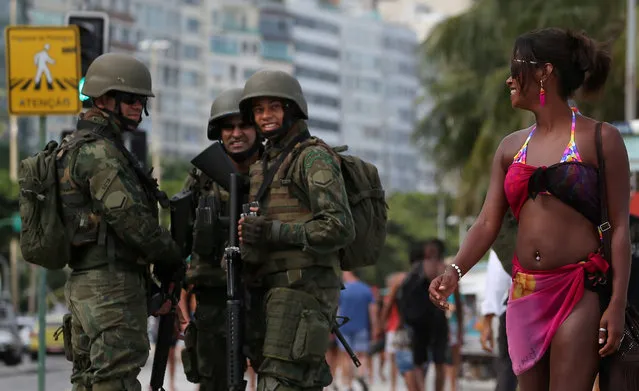 Brazilian navy soldiers watch a woman as they patrol the area at the Copacabana Beach before carnival festivities in Rio de Janeiro, Brazil February 14, 2017. (Photo by Sergio Moraes/Reuters)