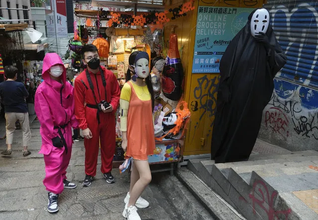 People in costumes pose for photos during Halloween along a street in Hong Kong, Sunday, October 31, 2021. (Photo by Vincent Yu/AP Photo)