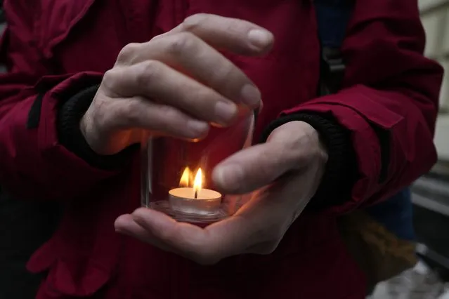 A demonstrator holds a candle as people gather in front of the Supreme Court of the Russian Federation in Moscow, Russia, Tuesday, December 14, 2021. The Supreme Court is continuing hearings on the liquidation of the Memorial human rights group. The authorities are ramping up pressure on the Soviet-rooted group, as part of its months-long crackdown on activists, independent media and opposition supporters. (Photo by Pavel Golovkin/AP Photo)