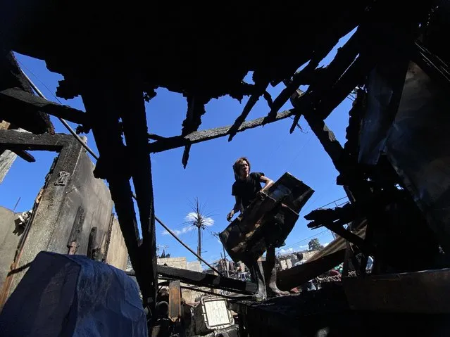 A resident scatters debris to retrieve belongings following a fire in a residential district of Las Pinas city, Metro Manila, Philippines, 02 April 2024. According to a report by the Philippines Bureau of Fire Protection (BFP), fire incidents between January and March are higher by 24 percent over the same period in 2023. Firefighters experienced a sharp increase in calls from households due to power overload and overheating of electric fans from non-stop usage, leading to fires. (Photo by Francis R. Malasig/EPA)