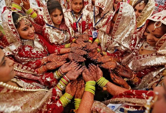Brides pose as they display their hands decorated with henna before taking their wedding vows during a mass marriage ceremony in which, according to its organizers, 131 Muslim couples took their wedding vows in Ahmedabad, India, February 26, 2017. (Photo by Amit Dave/Reuters)