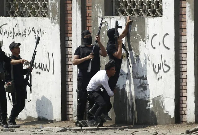 Riot police lift a comrade to fire tear gas during clashes in front of the Al-Azhar University's campus wall with students who are supporters of the Muslim Brotherhood and ousted Egyptian President Mohamed Mursi, in Cairo's Nasr City district March 30, 2014. The Muslim Brotherhood, which had propelled Mursi to power at the ballot box, accuses the army of staging a coup against a legitimately chosen president and destroying democracy. (Photo by Amr Abdallah Dalsh/Reuters)