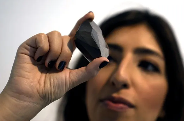 An employee of Sotheby's Dubai presents a 555.55 Carat Black Diamond “The Enigma” to be auctioned at Sotheby's Dubai gallery, in Dubai, United Arab Emirates, Monday, January 17, 2022. (Photo by Kamran Jebreili/AP Photo)