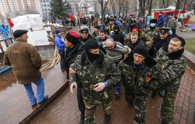 Pro-Russian protesters escort a man detained yesterday, who they said provoked them by trying to sell a pistol, near the seized office of the SBU state security service in Luhansk, in eastern Ukraine April 13, 2014. The man was handed over to local police. Government buildings in several towns in the Donetsk and Luhansk regions were attacked in what Washington said were moves reminiscent of the events that preceded Russia's annexation of Ukraine's Crimean peninsula. (Photo by Shamil Zhumatov/Reuters)