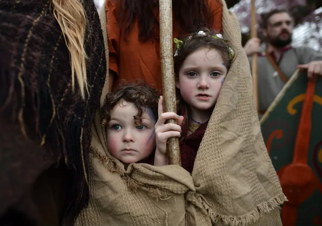 Forrest Bear Burns (L) and Willow Burns (R) huddle under their mother's shawl before they join their father, Marty Burns who plays the role of Saint Patrick, in the cross community Saint Patrick's Day parade on March 17, 2017 in Downpatrick, Northern Ireland. Tradition holds that Saint Patrick and his companions landed at the mouth of the Slaney river, a few miles from Down Cathedral, in 432 AD. From here Patrick travelled extensively spreading the teachings of Christianity before his death on 17th March 461 AD. He is buried at nearby Down Cathedral. (Photo by Charles McQuillan/Getty Images)