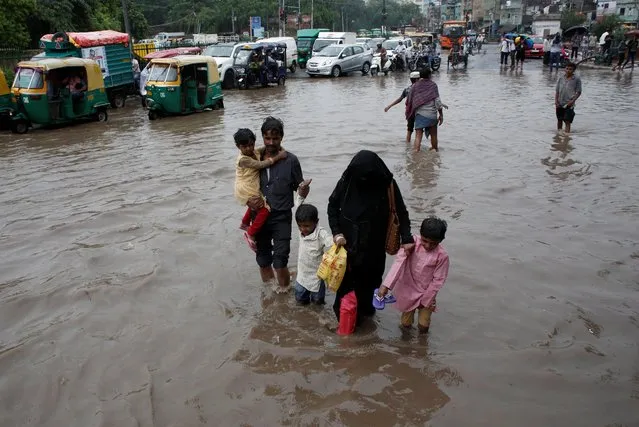 A family wades through a flooded street during heavy rains in New Delhi, India, August 6, 2019. (Photo by Adnan Abidi/Reuters)