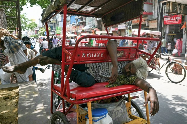 A man sleeps on his rickshaw along a street on a hot summer day in New Delhi on May 31, 2024. (Photo by Arun Sankar/AFP Photo)