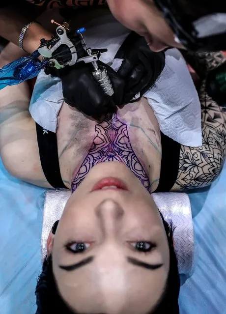 A tattoo artist applying ink on a girl' s chest during the 2017 Moscow Tattoo Festival at Moscow' s Amber Plaza Shopping Center in Moscow, Russia on April 1, 2017. (Photo by Valery Sharifulin/TASS)