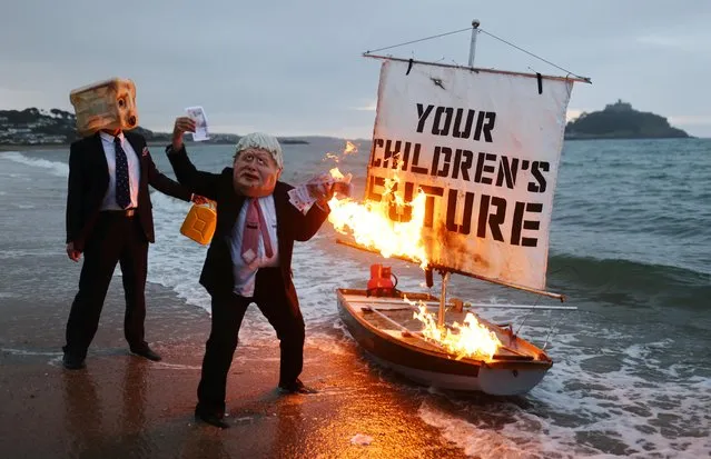 Activists from climate action group Ocean Rebellion set a boat on fire during a demonstration at sunrise at Marazion Beach, Cornwall, Britain, June 5, 2021, ahead of the G7 summit in Carbis Bay, Cornwall. (Photo by Tom Nicholson/Reuters)