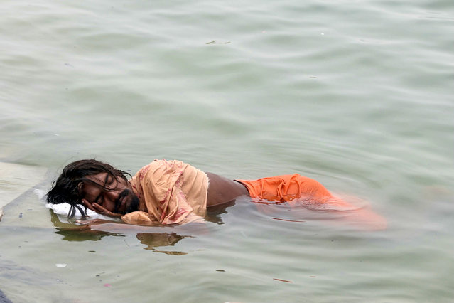 A man sleeps in the river Ganges on a hot summer day in Varanasi on June 18, 2024. (Photo by Niharika Kulkarni/AFP Photo)