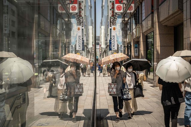 People using parasols to shelter from the sun walk in the Ginza area of Tokyo on June 14, 2024. (Photo by Yuichi Yamazaki/AFP Photo)