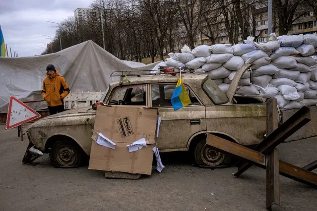 A militia man stands at a checkpoint set up on a road heading to the city of Kyiv, Ukraine, Saturday, March 5, 2022. Russian troops took control of the southern port city of Kherson this week. Although they have encircled Kharkiv, Mykolaiv, Chernihiv and Sumy, Ukrainian forces have managed to keep control of key cities in central and southeastern Ukraine, Ukrainian President Volodymyr Zelenskyy said Saturday. (Photo by Emilio Morenatti/AP Photo)