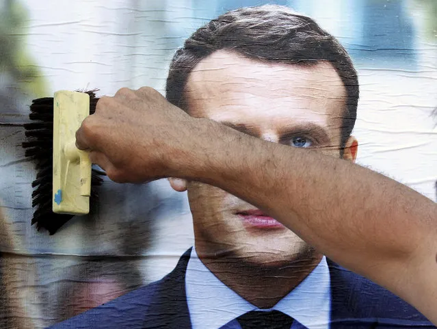 A supporter of French centrist presidential candidate Emmanuel Macron glues a campaign poster in Bayonne, southwestern France, Wednesday, April 19, 2017. The two-round presidential election is set for April 23 and May 7. (Photo by Bob Edme/AP Photo)