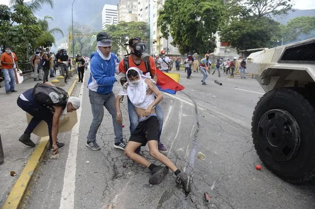 An opposition demonstrator ran over by a National Guard control vehicle is dragged away by a fellow demonstrator during a protest against Venezuelan President Nicolas Maduro, in Caracas on May 3, 2017. (Photo by Federico Parra/AFP Photo)