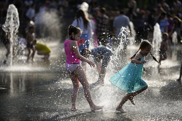 Girls cool off in a fountain at VDNKh (The Exhibition of Achievements of National Economy) enjoying the warm weather, in Moscow, Russia, on Sunday, June 30, 2024. Warm weather has settled in Moscow with a temperature of 31 Celsius, (87,8 Fahrenheit) and will increase in the coming days. (Photo by Alexander Zemlianichenko/AP Photo)