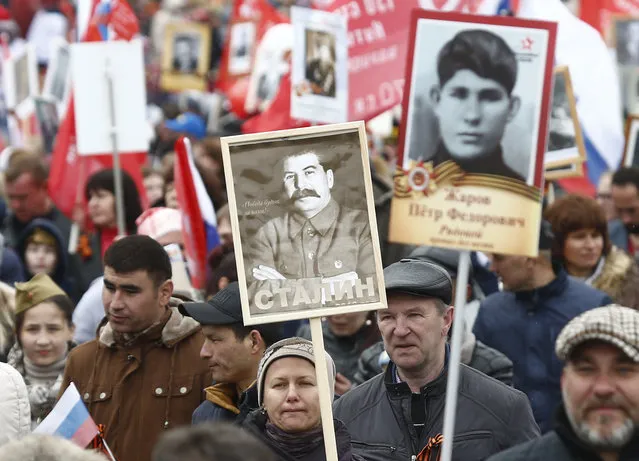 A woman holds a portrait of Soviet dictator Josef Stalin as she takes part in the Immortal Regiment march during the 72nd anniversary of the end of World War II on the Red Square in Moscow, Russia on May 9, 2017. (Photo by Maxim Shemetov/Reuters)