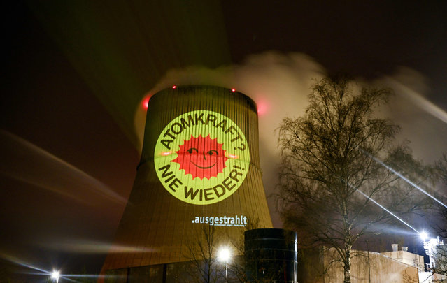 Activists of the nationwide anti-nuclear organisation “ausgestrahlt” illuminate a cooling tower of the nuclear power plant Emsland run by German energy company RWE with the slogan “Nuclear energy – never again” in Lingen, western Germany on April 10, 2023. Germany will shut down its three remaining nuclear plants on April 15, betting that it can fulfil its green ambitions without atomic power despite the energy crisis caused by the Ukraine war. The cloud of white steam that has risen since 1989 over the river in Neckarwestheim, near Stuttgart, will soon be a distant memory, as will the Isar 2 complex in Bavaria and the Emsland plant in the north. Following the shutdown of the Emsland nuclear power plant, operator RWE expects the initial decommissioning phase, including post-operation, to last 14 years. (Photo by  Ina Fassbender/AFP Photo)